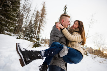 Man holding woman in his arms - snowy winter.