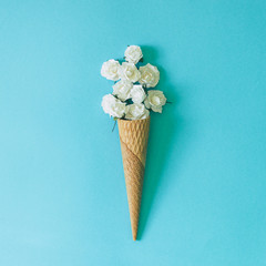 Ice cream cone with white flowers and leaves. Summer minimal concept. Flat lay