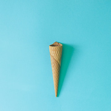 Empty ice cream cone on bright blue background. Minimal food concept. Flat lay