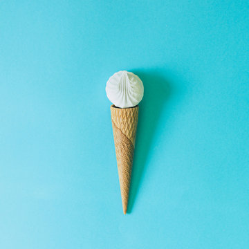 Ice cream cone and delicate souffle or marshmallow on pastel blue background. Abstract concept of food. Minimal flat lay.