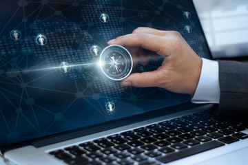 Businessman holding compass  and icon customer network connection on screen laptop background, m-banking and omni channel © ipopba