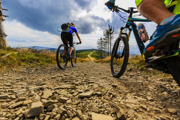 Fototapeta na wymiar Mountain biking women and man riding on bikes at sunset mountains forest landscape. Couple cycling MTB enduro flow trail track. Outdoor sport activity.