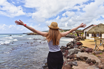 Tourist woman in hat on the beach with raised hands