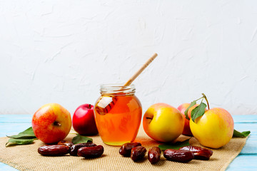 Honey jar, dates and ripe apples on burlap napkin