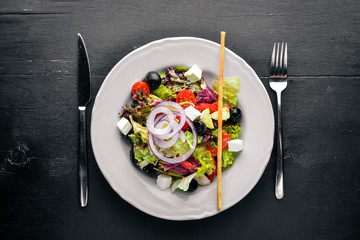 Greek salad. Fresh vegetables on a wooden background. Top view. Free space for text.