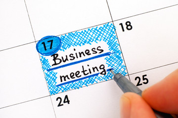 Woman fingers with pen writing reminder Business meeting in calendar.