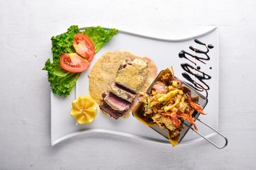 Veal steak and grilled vegetables. On a wooden background. Top view. Free space for text.