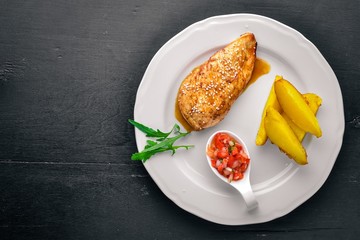 Chicken steak and potatoes on a wooden background. Top view. Free space for text.