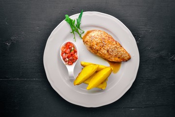 Chicken steak and potatoes on a wooden background. Top view. Free space for text.