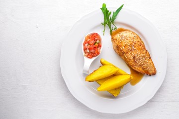 Chicken steak and potatoes on a wooden background. Top view. Free space for text.