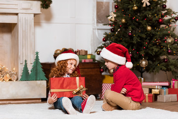 Obraz na płótnie Canvas kids in santa claus hats with gift