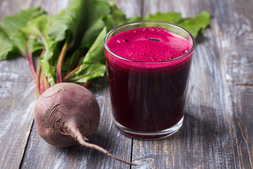 Fresh beet juice in glasses with a straw on a wooden background, selective focus. Healthy detox diet