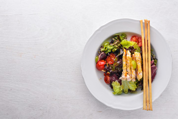 Vegetable salad with chicken and mango sauce on a wooden background. Top view. Free space for text.