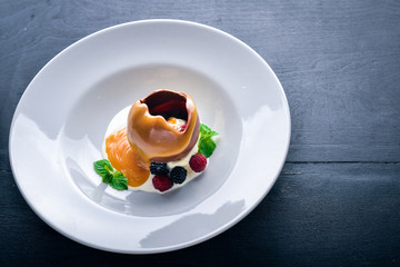 Ice-cream with wild berries and chocolate. On a wooden background. Top view. Free space for text.