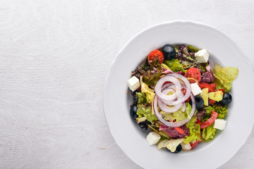 Greek salad. Fresh vegetables on a wooden background. Top view. Free space for text.