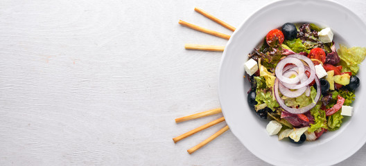 Greek salad. Fresh vegetables on a wooden background. Top view. Free space for text.