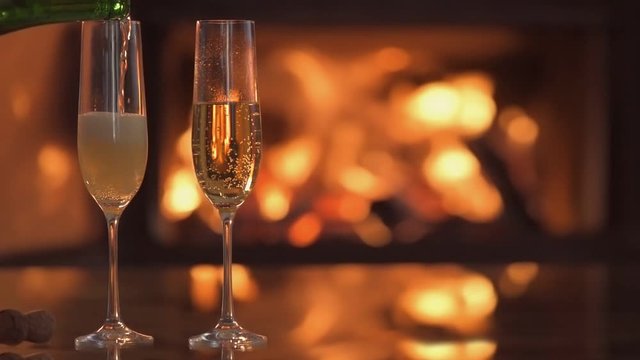 Cinemagraph -Champagne in two glasses on table in front of burning fireplace. Motion Photo.
