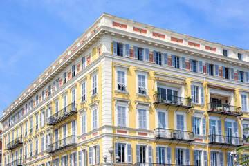 Fototapeta na wymiar Daylight view to yellow building of a hotel in Nice Cote d'Azur, France. Blue sky background.