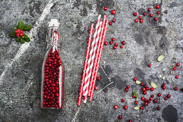 Bottle full of berries fresh ripe northern lingonberry with straws for a cocktail. The concept of healthy drinks from organic products. Top View.