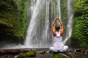 Woman meditating doing yoga between waterfalls