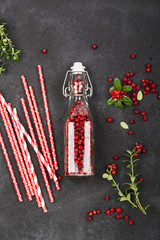 Bottle full of berries fresh ripe northern lingonberry with straws for a cocktail. The concept of healthy drinks from organic products. Top View.