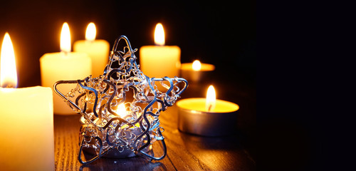 Merry Christmas and happy New Year. A warm dark golden brown wooden background with burning candles...
