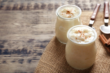 Creamy rice pudding with cinnamon powder on wooden table