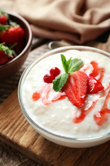 Creamy rice pudding with strawberry on wooden board