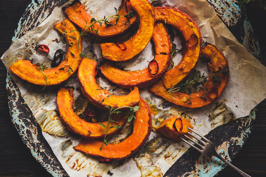Delicious baked pumpkin with thyme and chilli on the wooden table, top view