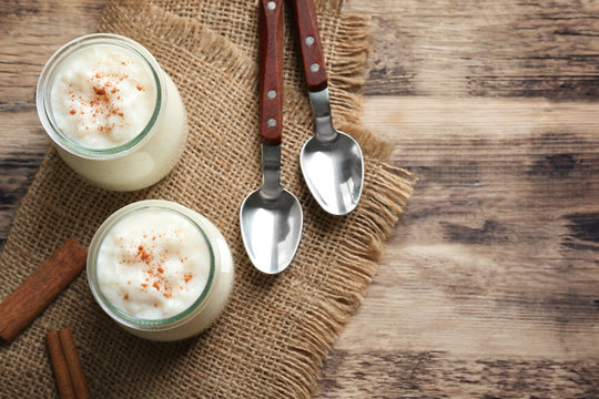 Creamy rice pudding with cinnamon powder on wooden table