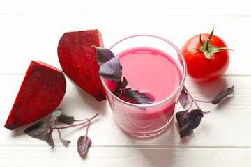 Glass with fresh vegetable juice and ingredients on wooden table