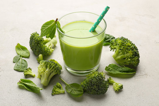 Glass with fresh green juice and ingredients on table