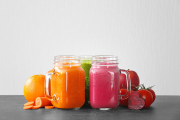 Mason jars with fresh juices and ingredients on table