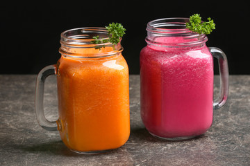 Mason jars with fresh vegetable juices on table