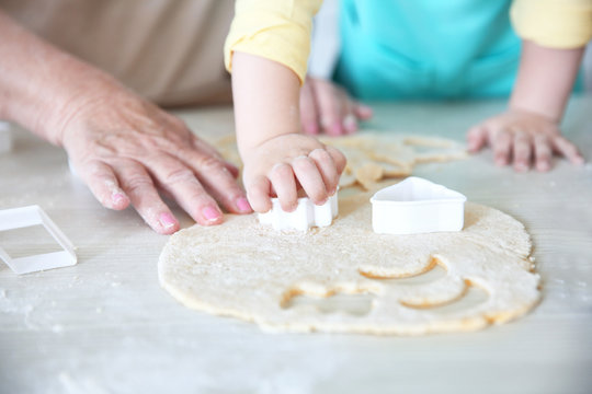 Little girl and her grandmother making cookies on kitchen