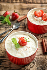 Creamy rice pudding with strawberry on wooden table