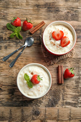 Creamy rice pudding with strawberry on wooden table