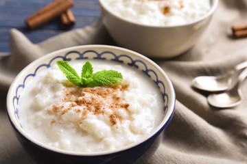 Creamy rice pudding with cinnamon powder in bowl on table, closeup