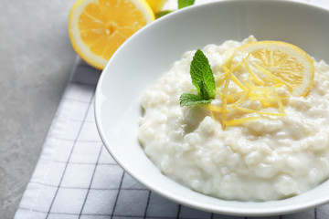 Creamy rice pudding with lemon in plate on table