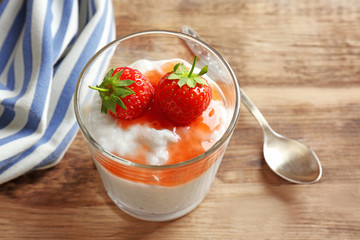Creamy rice pudding with strawberry in glass on wooden table