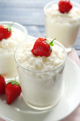 Creamy rice pudding with strawberry in glasses on table, closeup