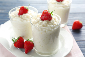 Creamy rice pudding with strawberry in glasses on table