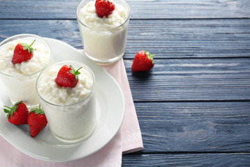 Creamy rice pudding with strawberry in glasses on table