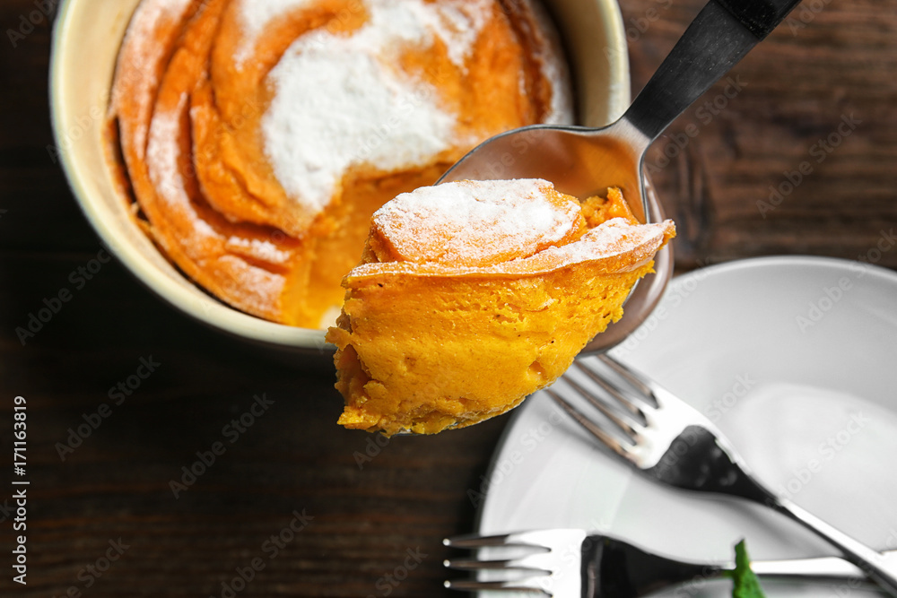 Wall mural spoon with tasty carrot souffle on blurred background