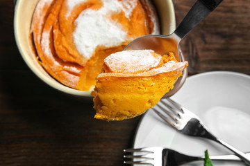 Spoon with tasty carrot souffle on blurred background