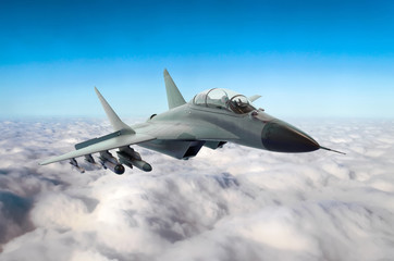 Fototapeta na wymiar Military fighter jet flies in the sky above the clouds