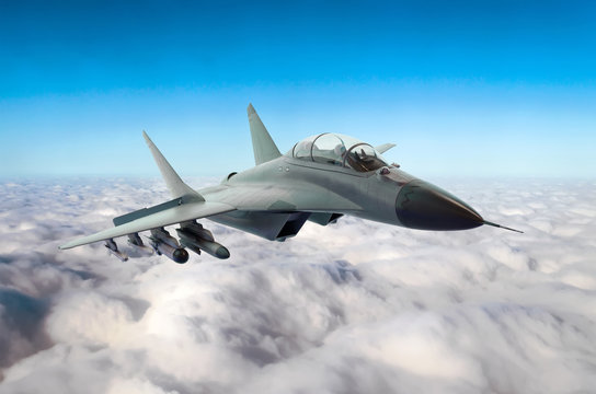 Military fighter jet flies in the sky above the clouds