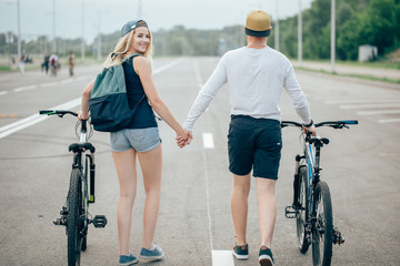 man and woman walk their bikes down the road