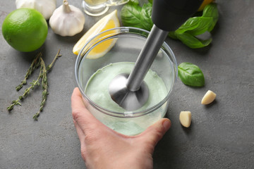 Woman preparing creamy lime sauce for fish taco in blender bowl on kitchen table