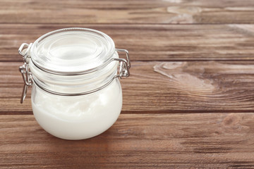 Coconut oil in jar on wooden background